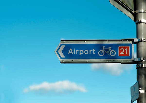 A road sign for the airport with a bicycle icon on it